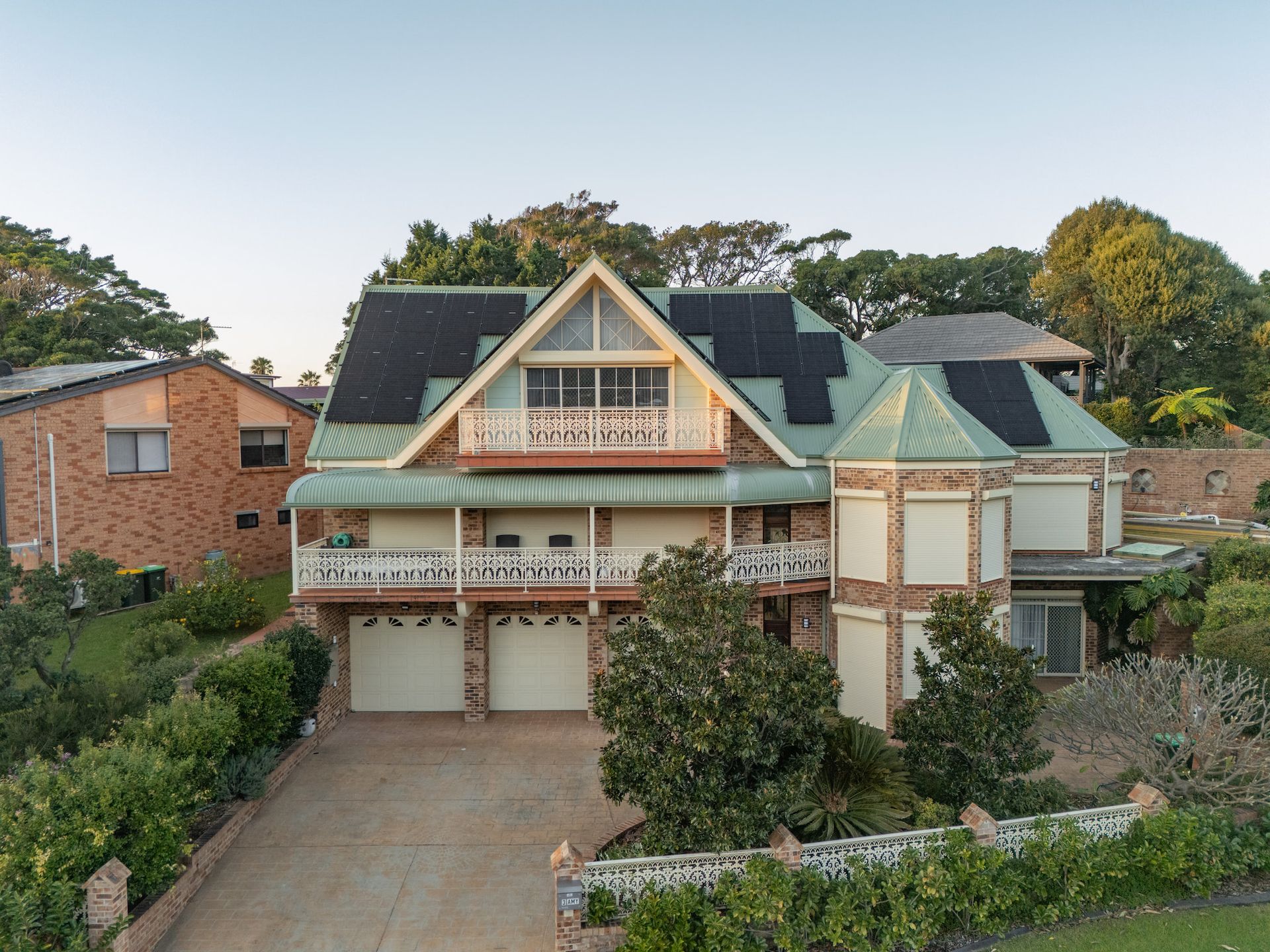 A large brick house with green metal roof and solar panels — GT Metal Roofing Solutions in Shellharbour, NSW