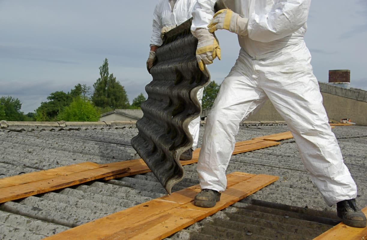 Two Men in White Overalls Are Carrying a Piece of Asbestos — GT Metal Roofing Solutions in Wollongong, NSW