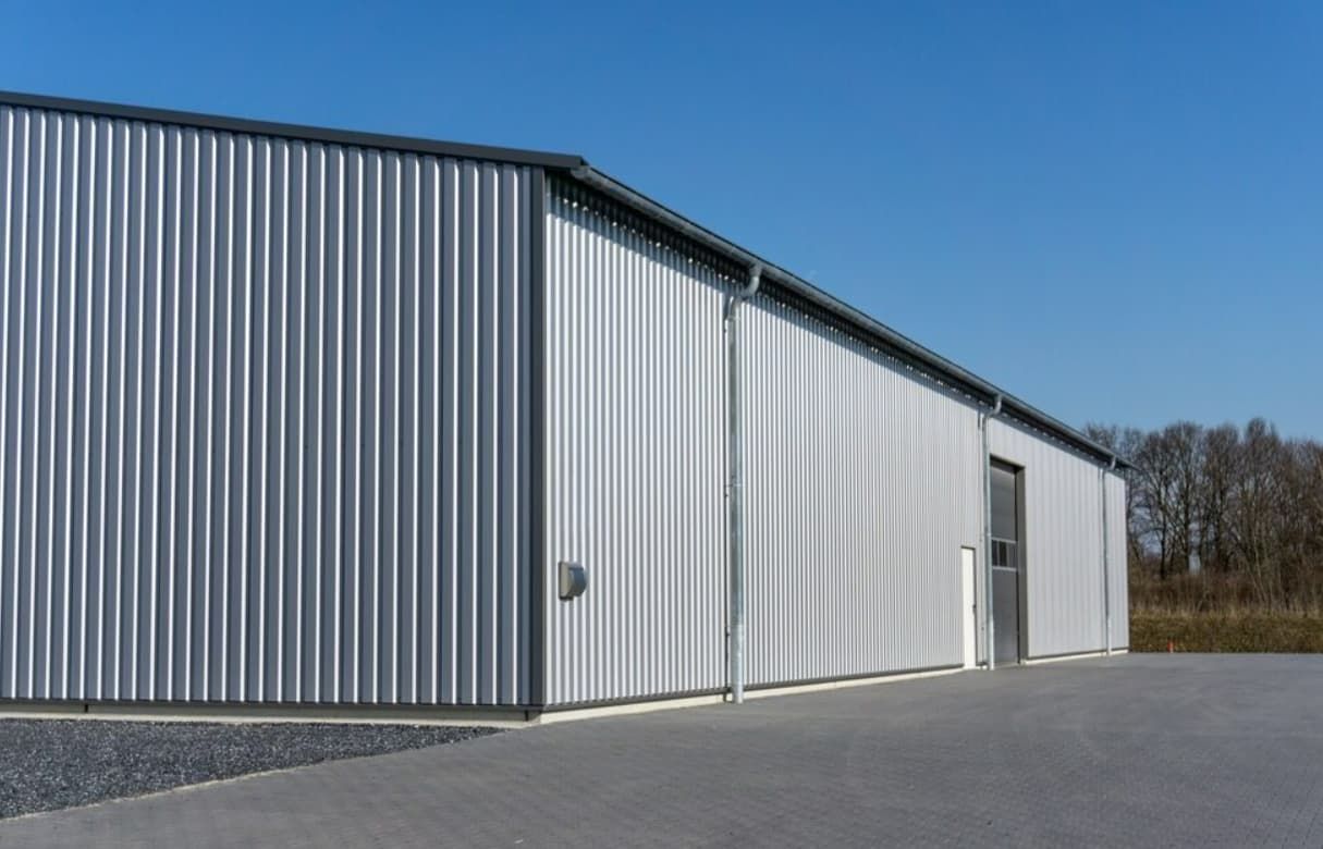 A Large Metal Building With a Blue Sky in the Background — GT Metal Roofing Solutions in Wollongong, NSW