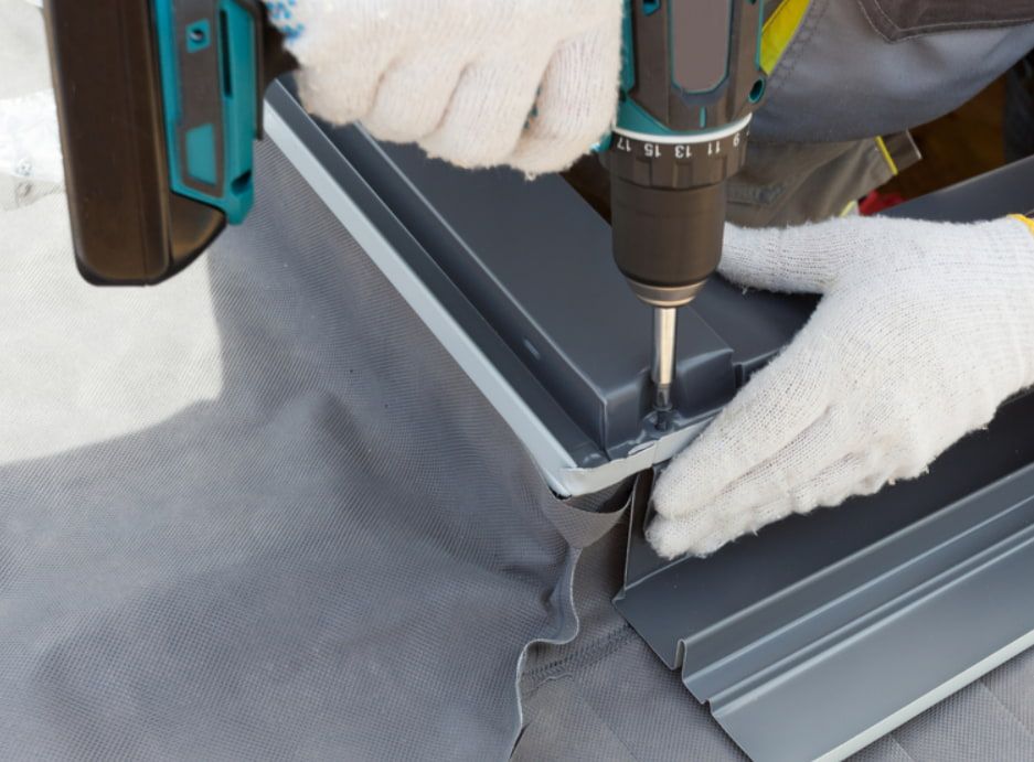 A Person is Using a Drill to Drill a Hole in a Piece of Metal — GT Metal Roofing Solutions in Shellharbour, NSW