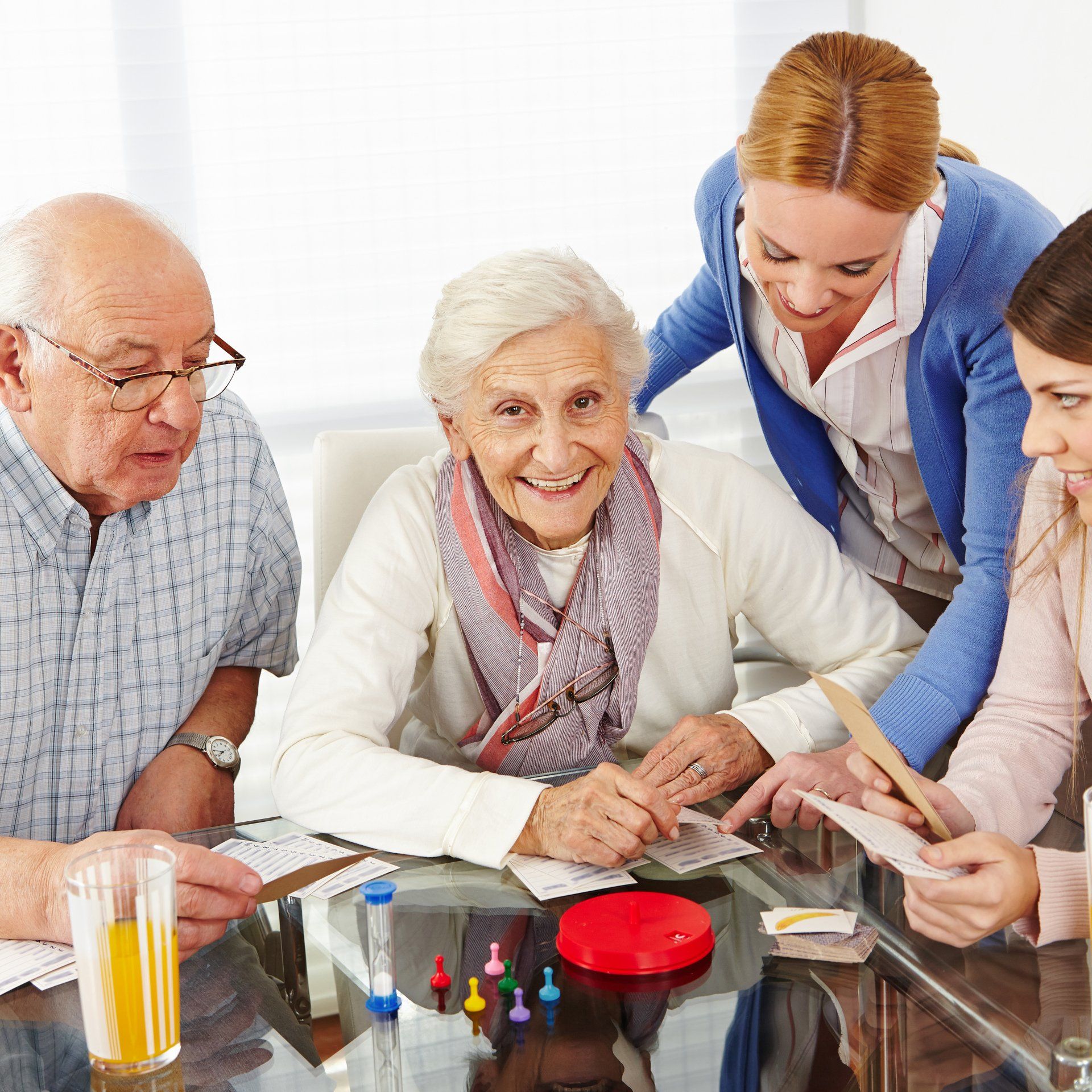 Group of people playing a game at a table; older adults with two younger women smiling and interacting.