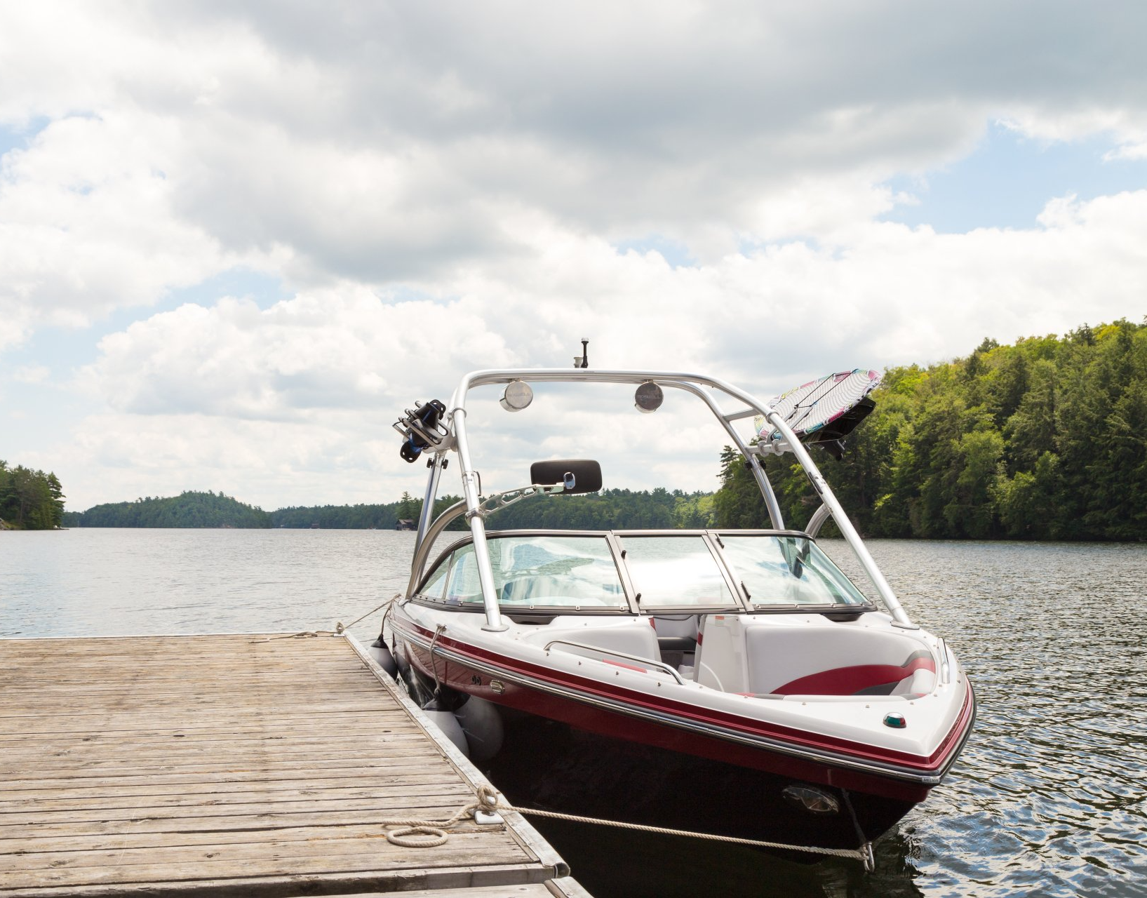 Motorboat docked on wooden pier at a lake.