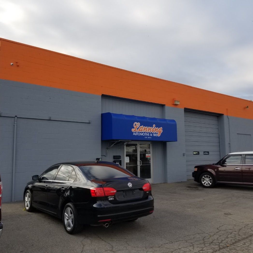Storefront with blue awning and orange-gray facade, with parked cars in front. | Lanning Automotive & Tire