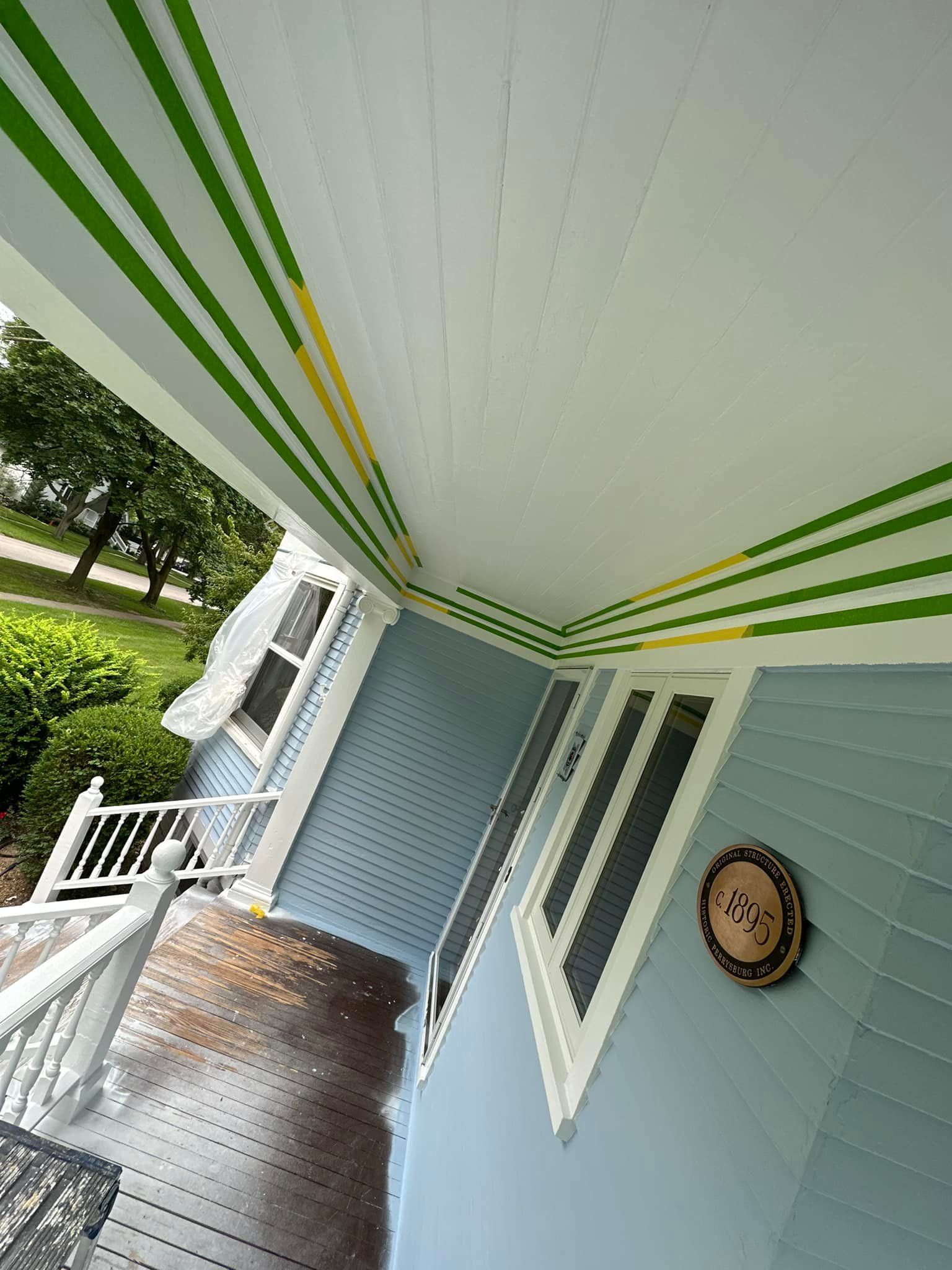 Blue house porch with white trim, green and yellow stripes on the ceiling.