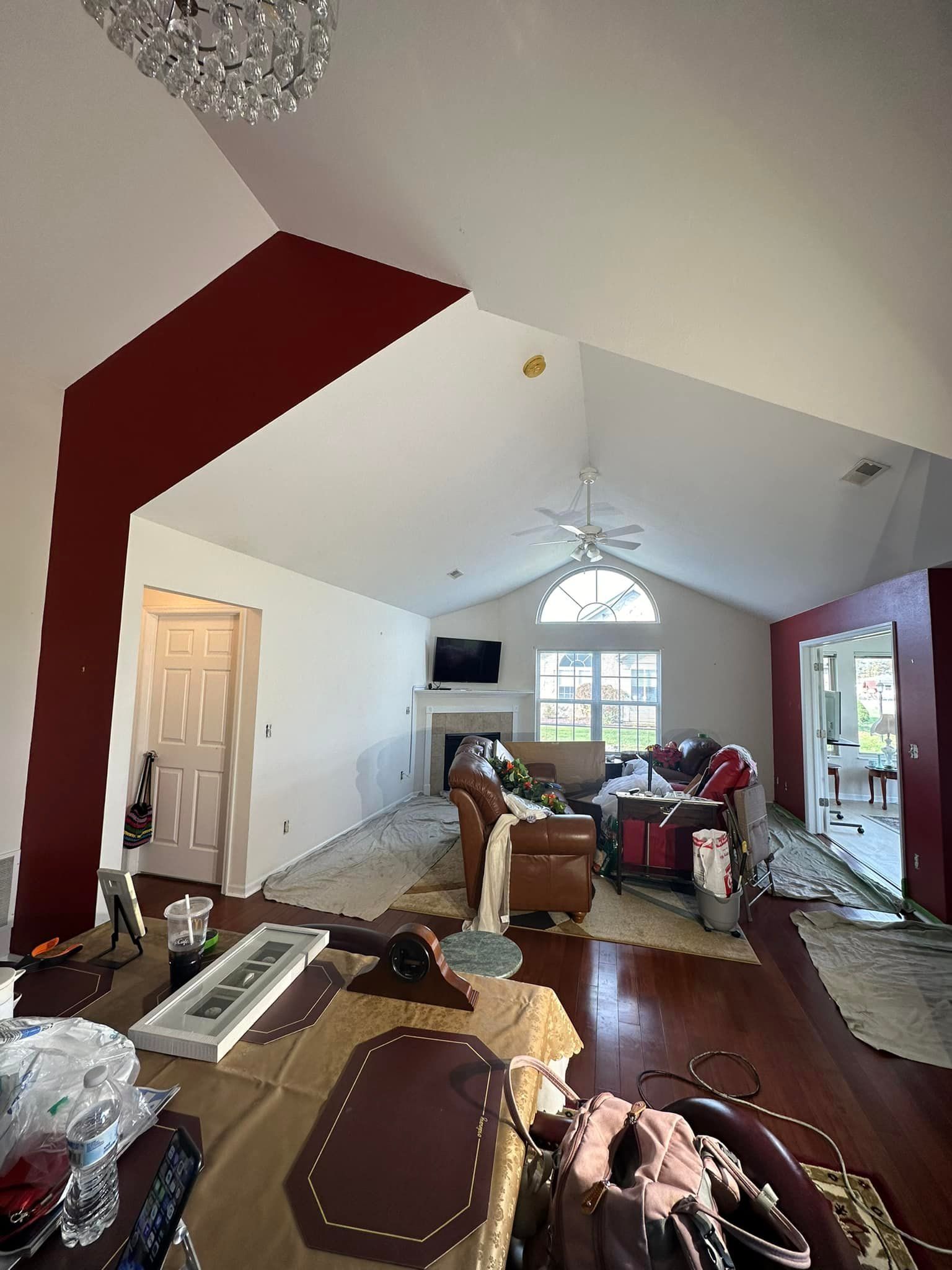Living room with a vaulted ceiling, partially painted, with red accent walls and chandelier.