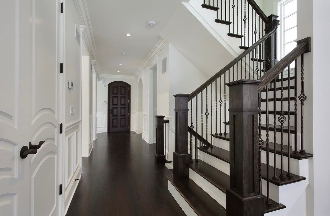 Staircase leading up with gray steps. Light and shadows are cast on the right wall. A door is at the top.