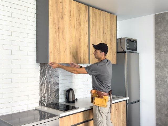 Person installing a wooden cabinet door in a white kitchen