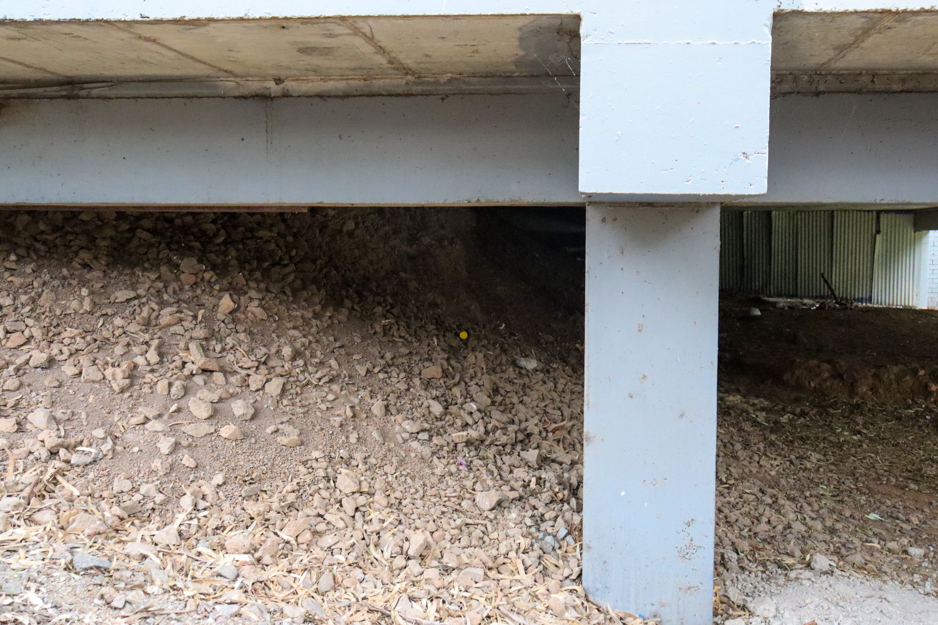 A concrete slab beneath a home, surrounded by dirt and gravel.