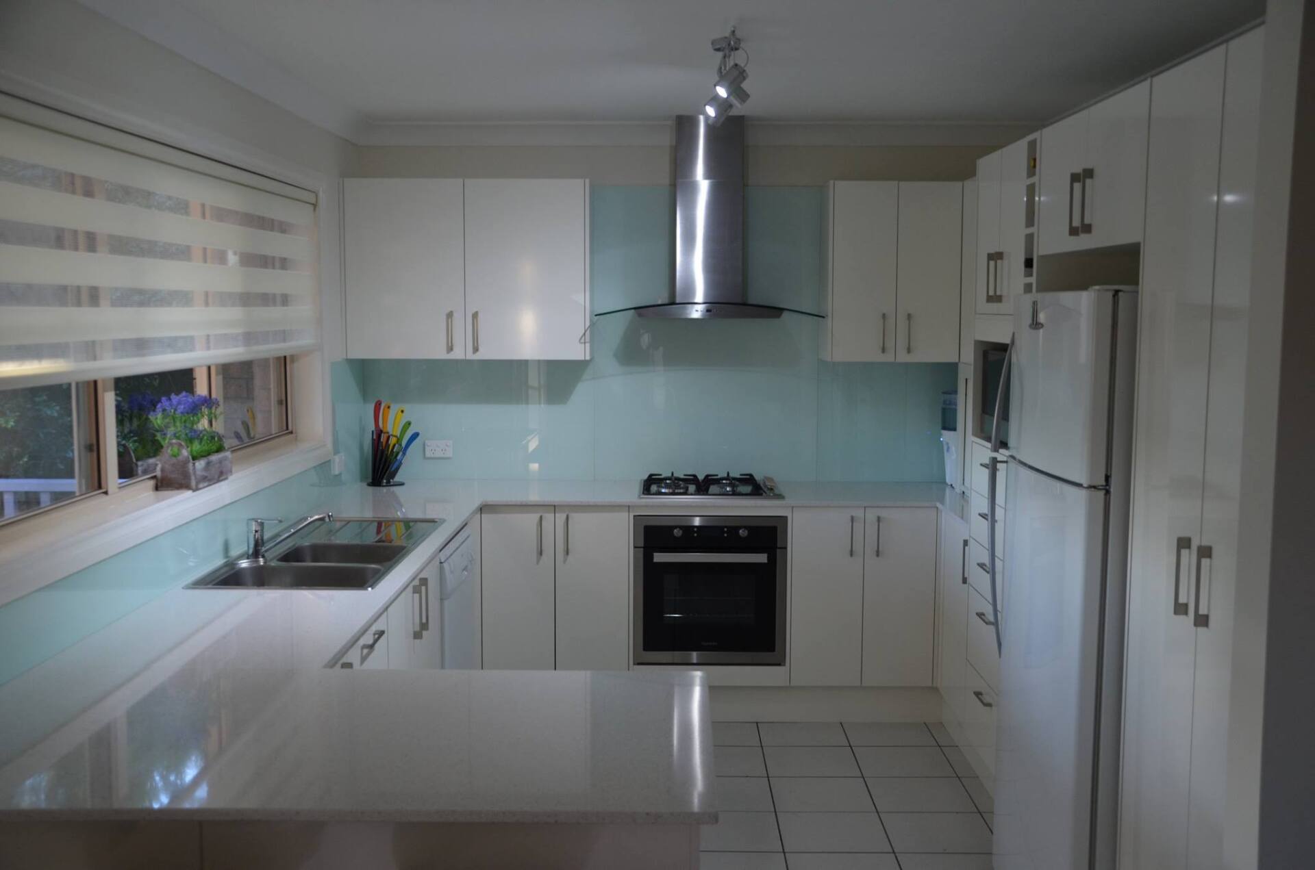 Modern White Kitchen With Light Blue Splashback — Kitchen Design Experts in Central Coast, NSW