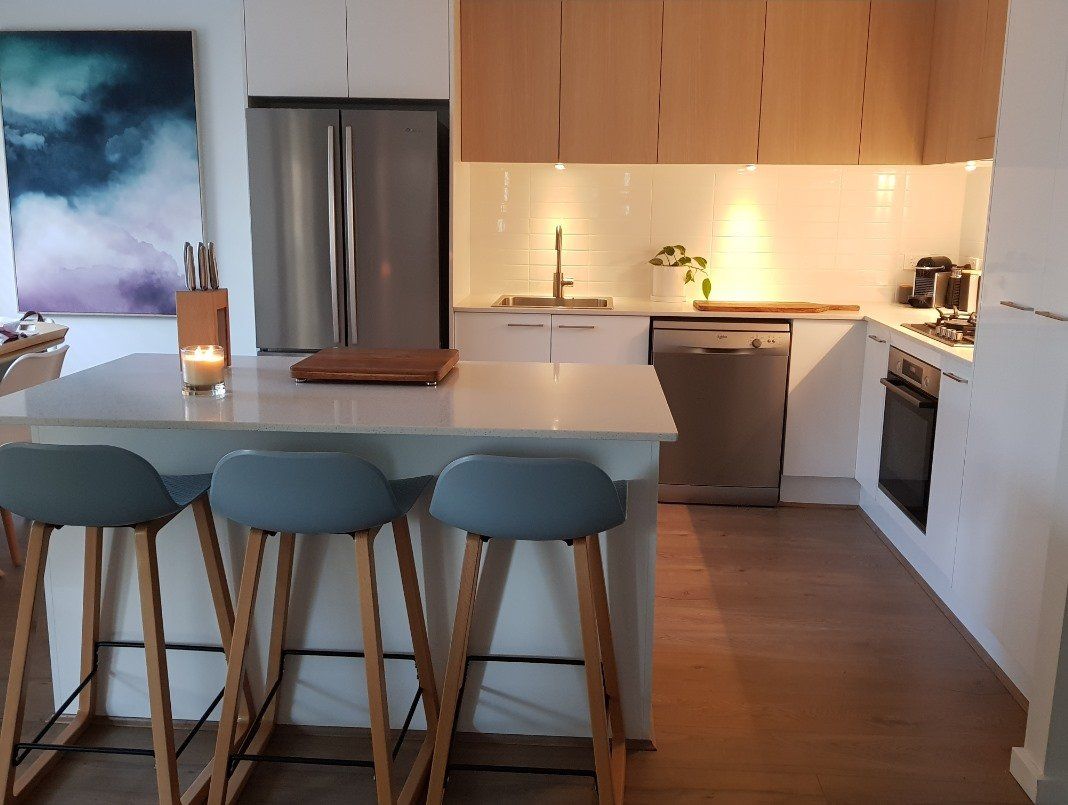 White Kitchen With Wooden Cabinets And Bar Stools — Kitchen Design Experts in Central Coast, NSW