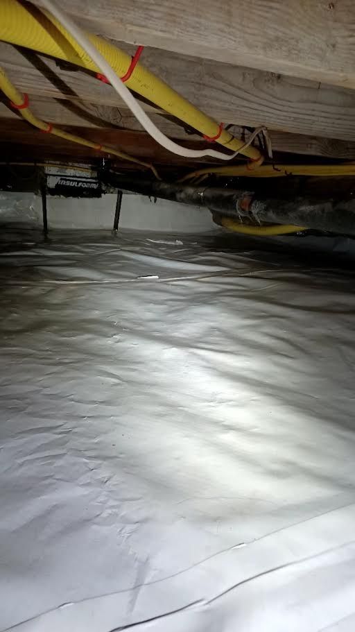 Insulated crawlspace floor with pipes and wires under wooden beams
