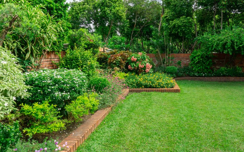 Lush Green Lawn in a Well-kept Garden, With Flower Beds and a Brick Border — Hanta Mowing Services Townsville in Kirwan, QLD