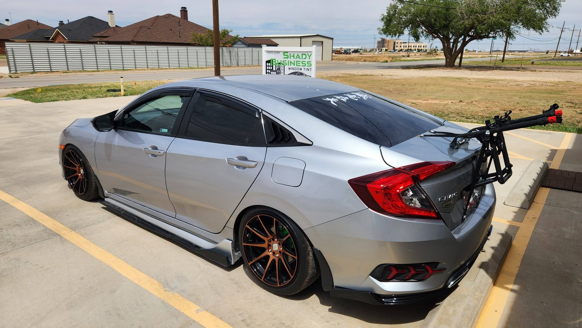 Silver sports sedan in a parking lot with a rear-mounted bike rack, side view.