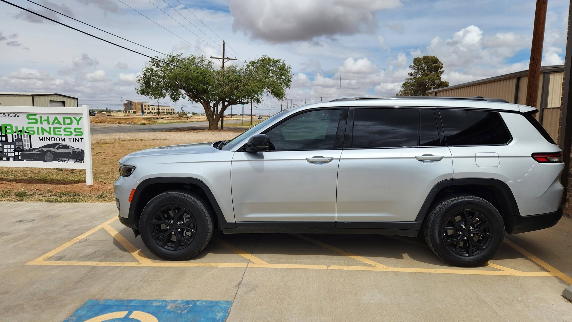 Silver SUV parked in a lot under a partly cloudy sky