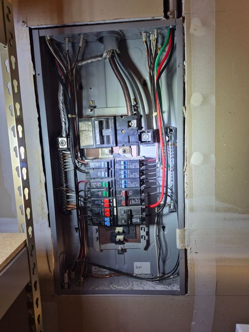Open electrical panel with circuit breakers and colorful wiring in a wall cabinet