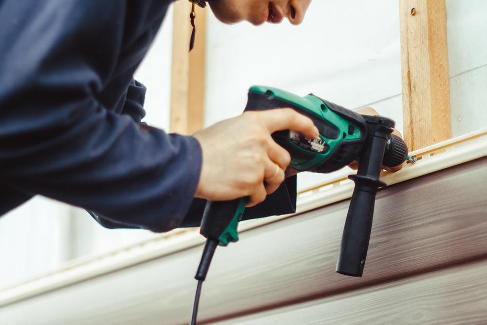 A man skilfully uses a drill for new home siding installation in Champaign & Springfield, IL, enhanc