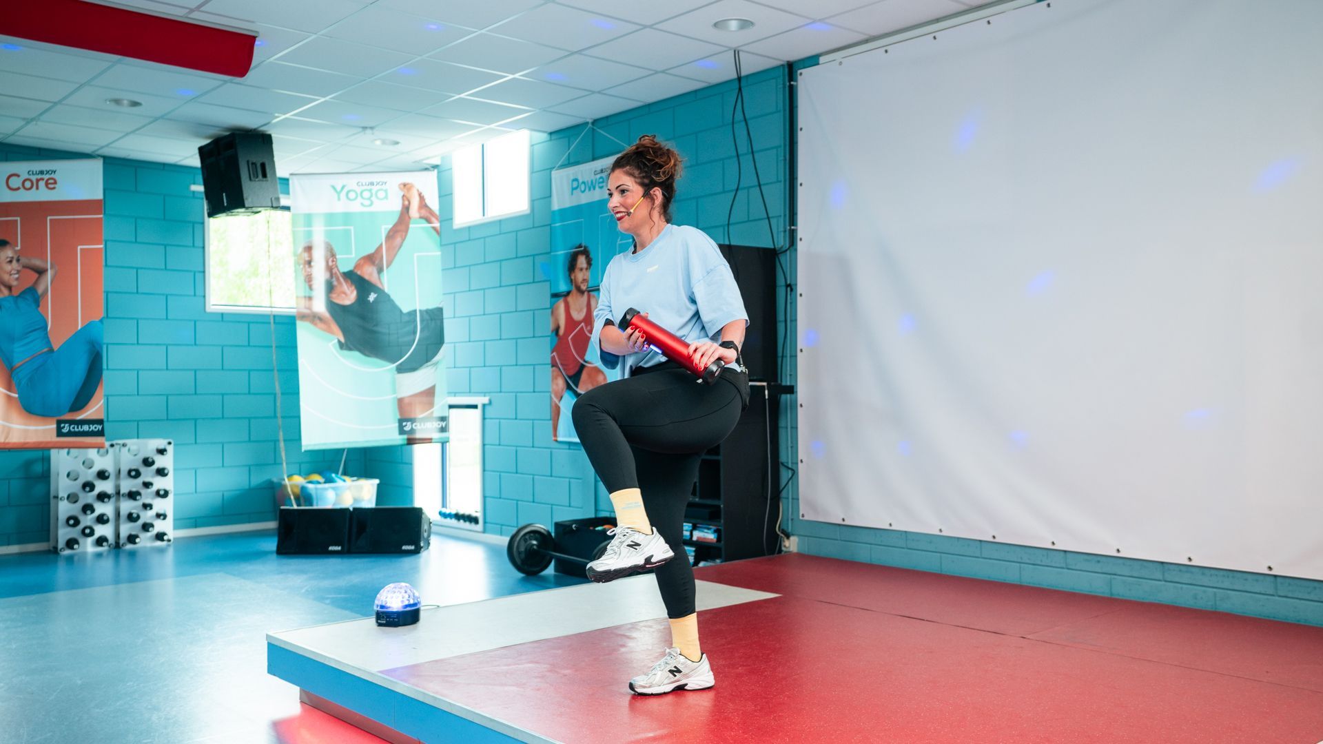 Vrouw in de sportschool doet een dumbbell row-oefening. Blauwe en witte kamer met apparatuur.