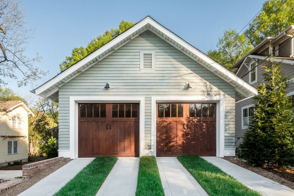 A garage with two wooden garage doors is sitting next to a house.