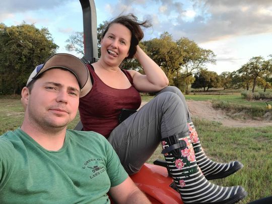 Oliver and Jenna are sitting on a tractor in a field.