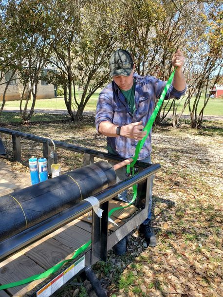 A man is working on a pipe with a green hose.