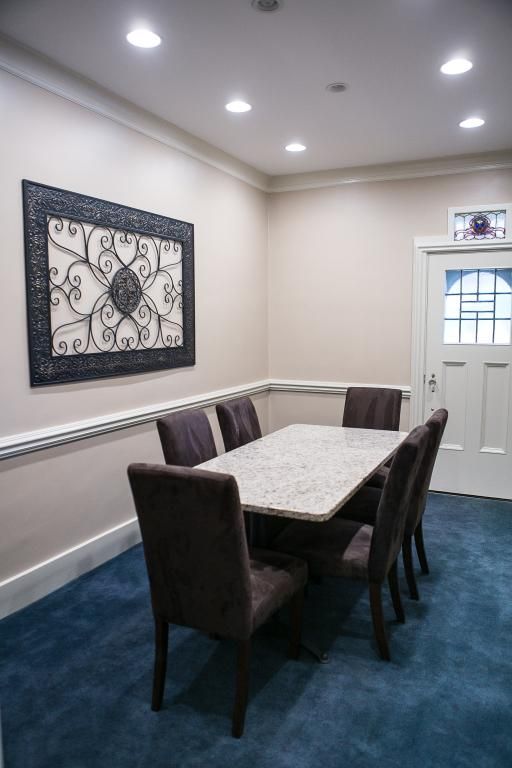 Dining room with a table, six chairs, decorative wall art, and blue carpet.
