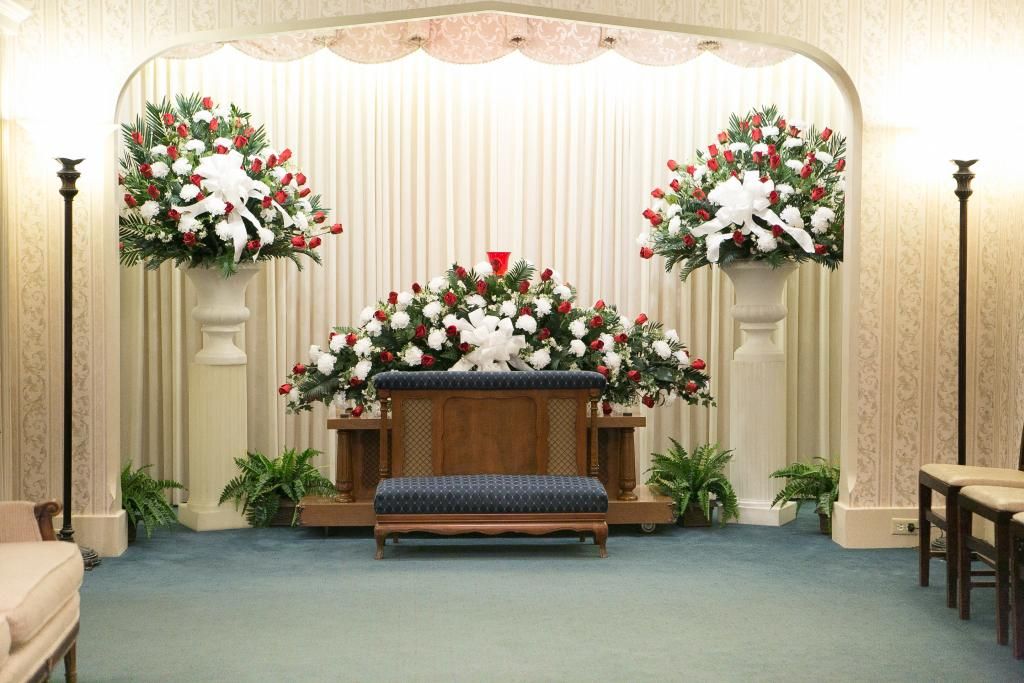 Funeral home setting with floral arrangements and seating.