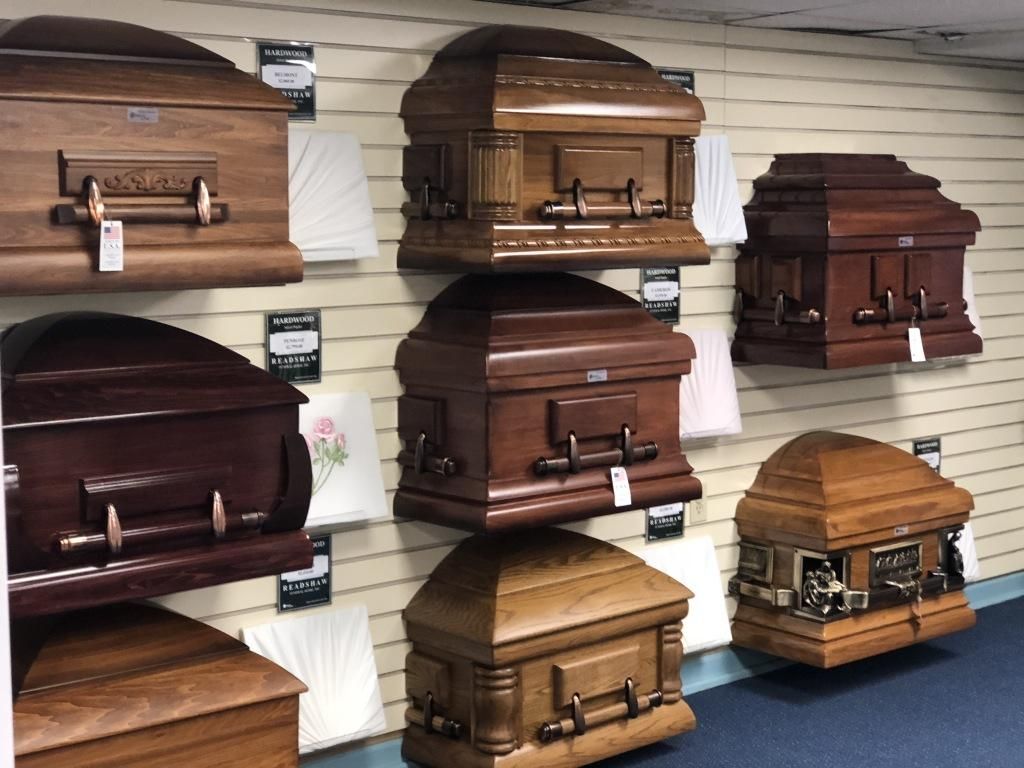 Wooden coffins on display in a funeral home. Dark brown and light brown wood.