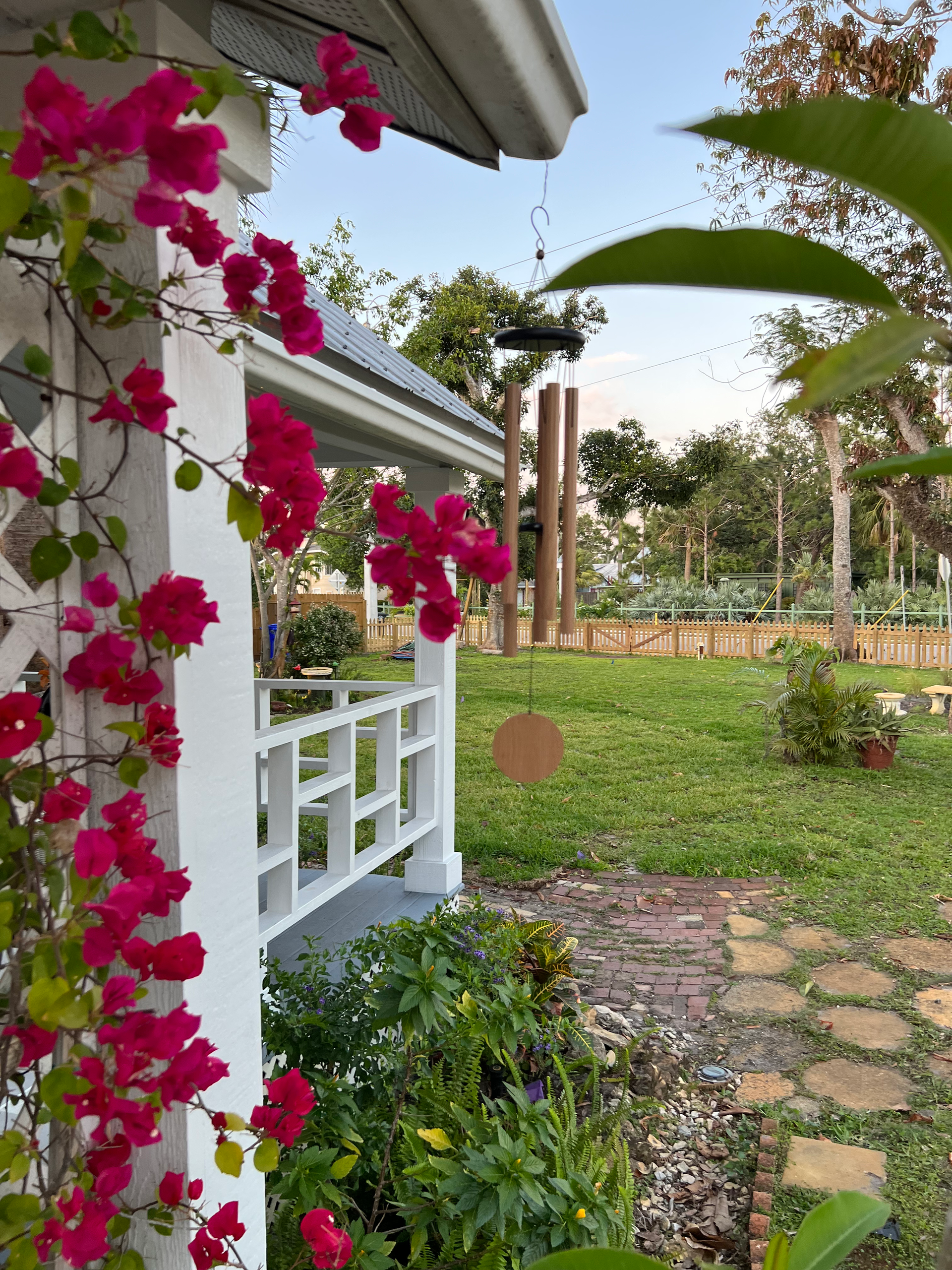 A white porch with pink flowers growing on it.