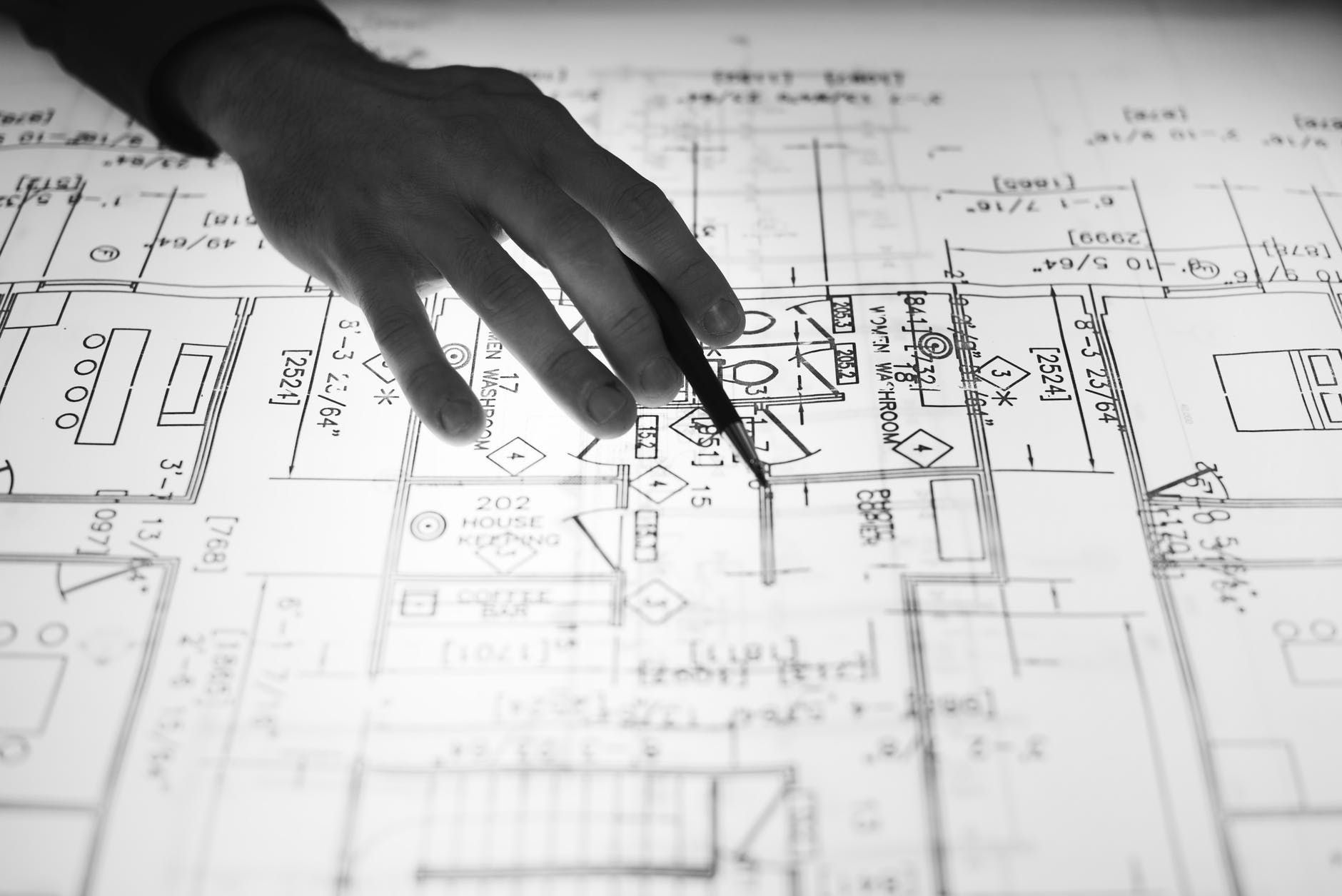A person is pointing at a floor plan with a pen