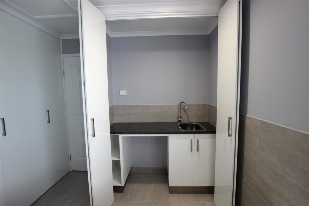 An Empty Kitchen With White Cabinets and a Sink — Mackay Cabinetmaking Service In Rural View, QLD