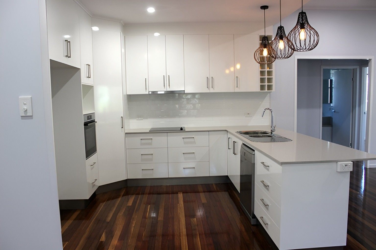 A Kitchen With White Cabinets and a Wooden Floor — Mackay Cabinetmaking Service In Sarina, QLD