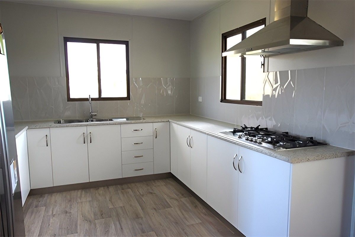 A Kitchen With White Cabinets and a Stove Top Oven — Mackay Cabinetmaking Service In Glenella, QLD