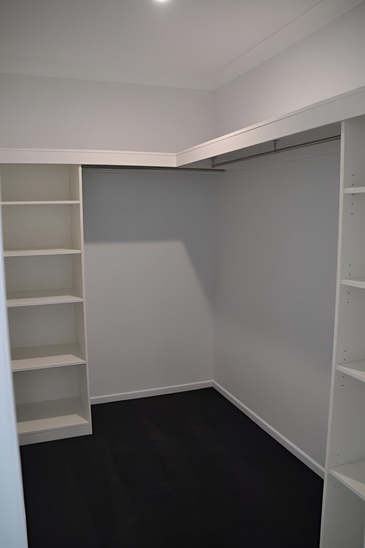 A Walk in Closet With White Shelves and Black Carpet — Mackay Cabinetmaking Service In Moranbah, QLD