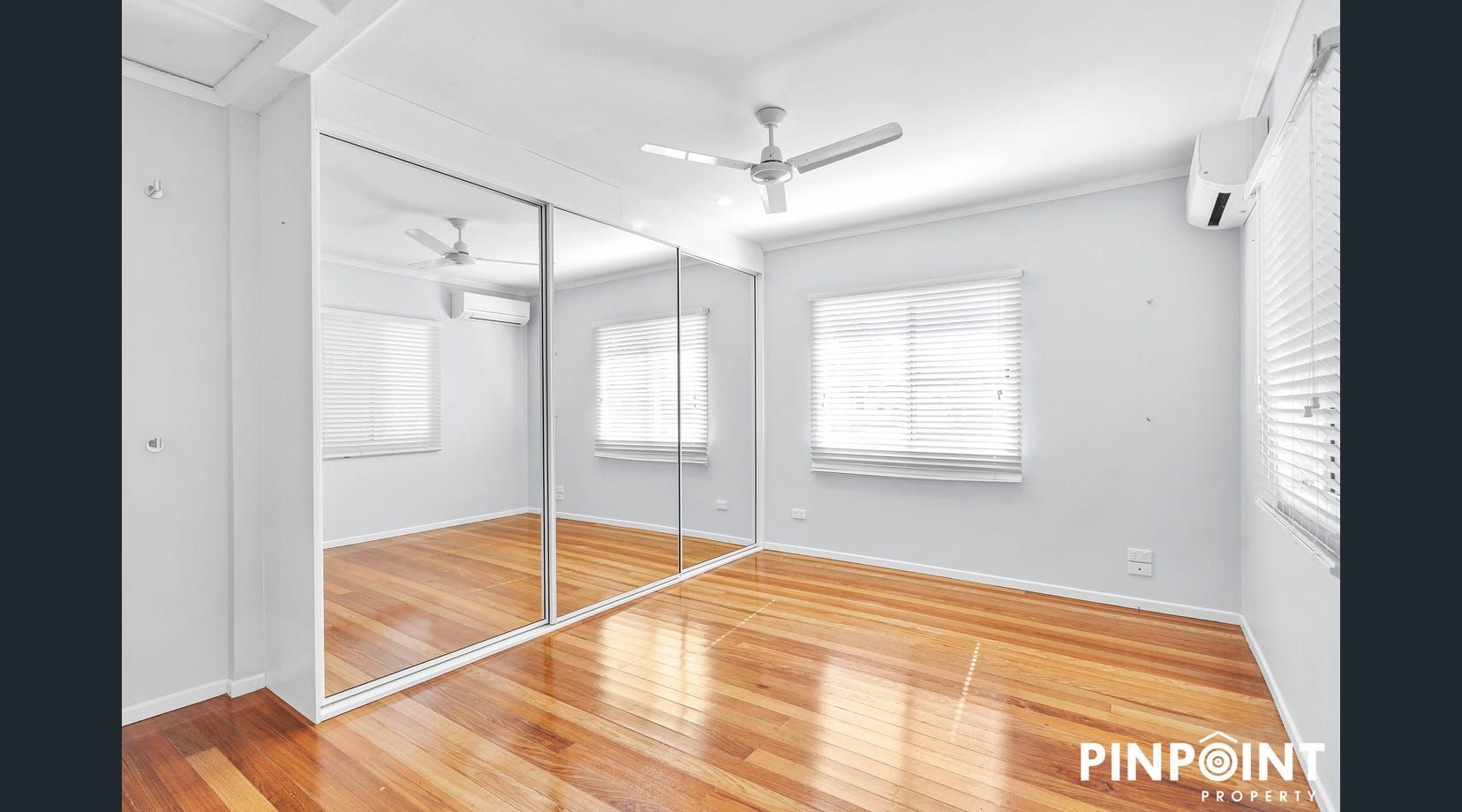 Bright empty bedroom with mirrored closet and white walls — Mackay Cabinetmaking Service In Glenella, QLD