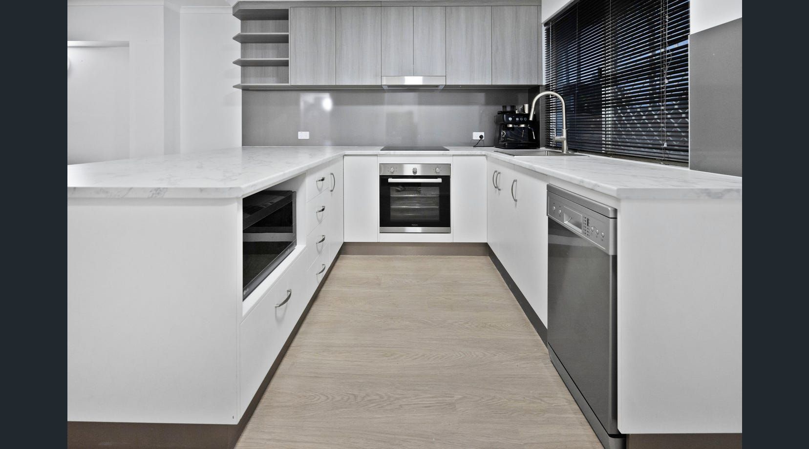 Modern white kitchen with island and stainless appliances — Mackay Cabinetmaking Service In Glenella, QLD