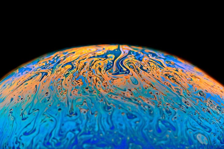 Colorful orange and blue swirling liquid patterns on a dark background