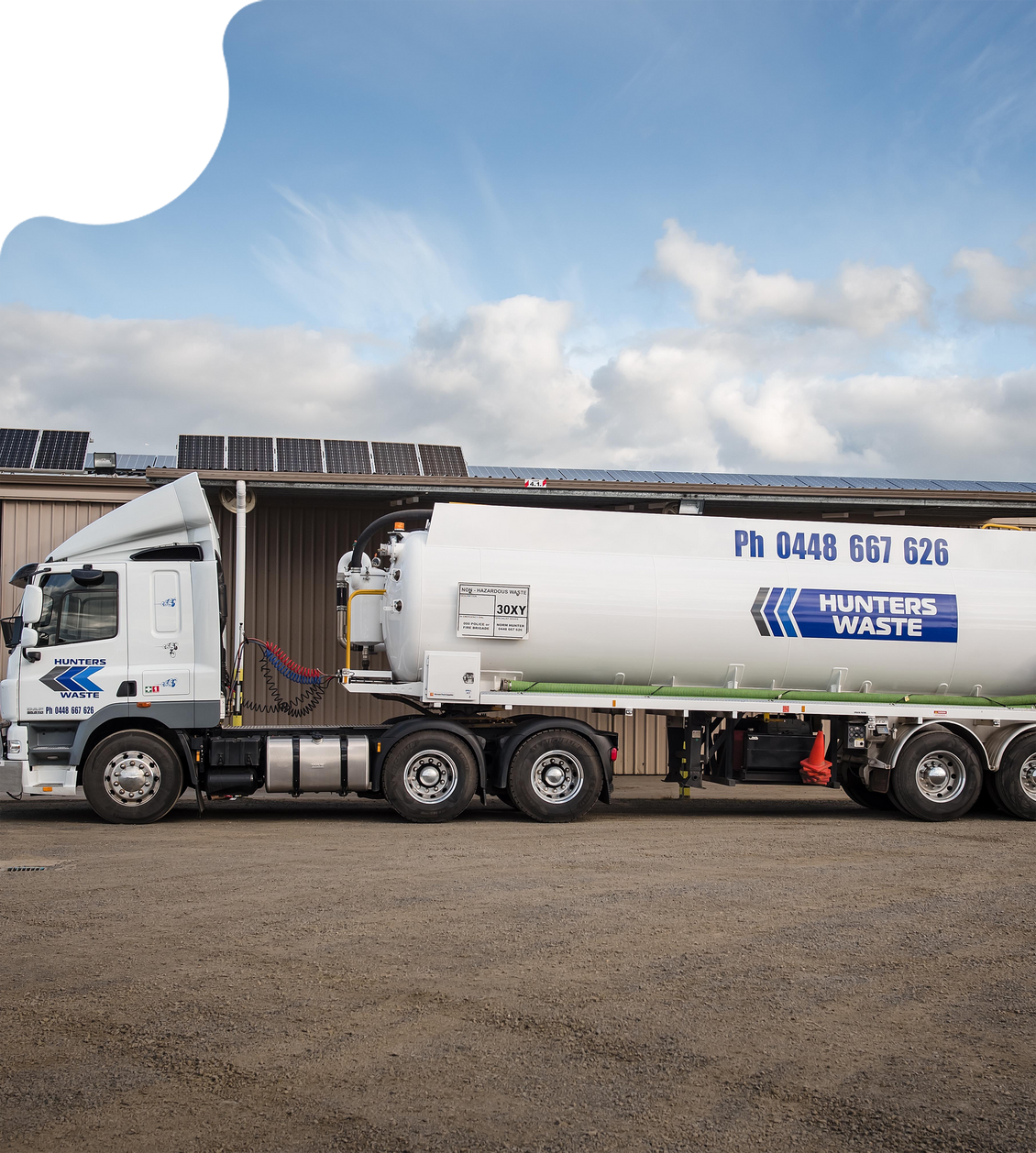 White tanker truck parked outdoors under a partly cloudy sky.