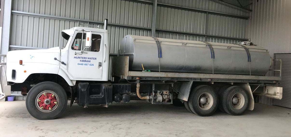 White tanker truck parked inside a warehouse loading bay