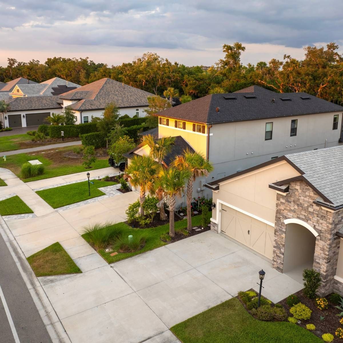 Suburban homes with driveways and landscaping under a warm sunset.