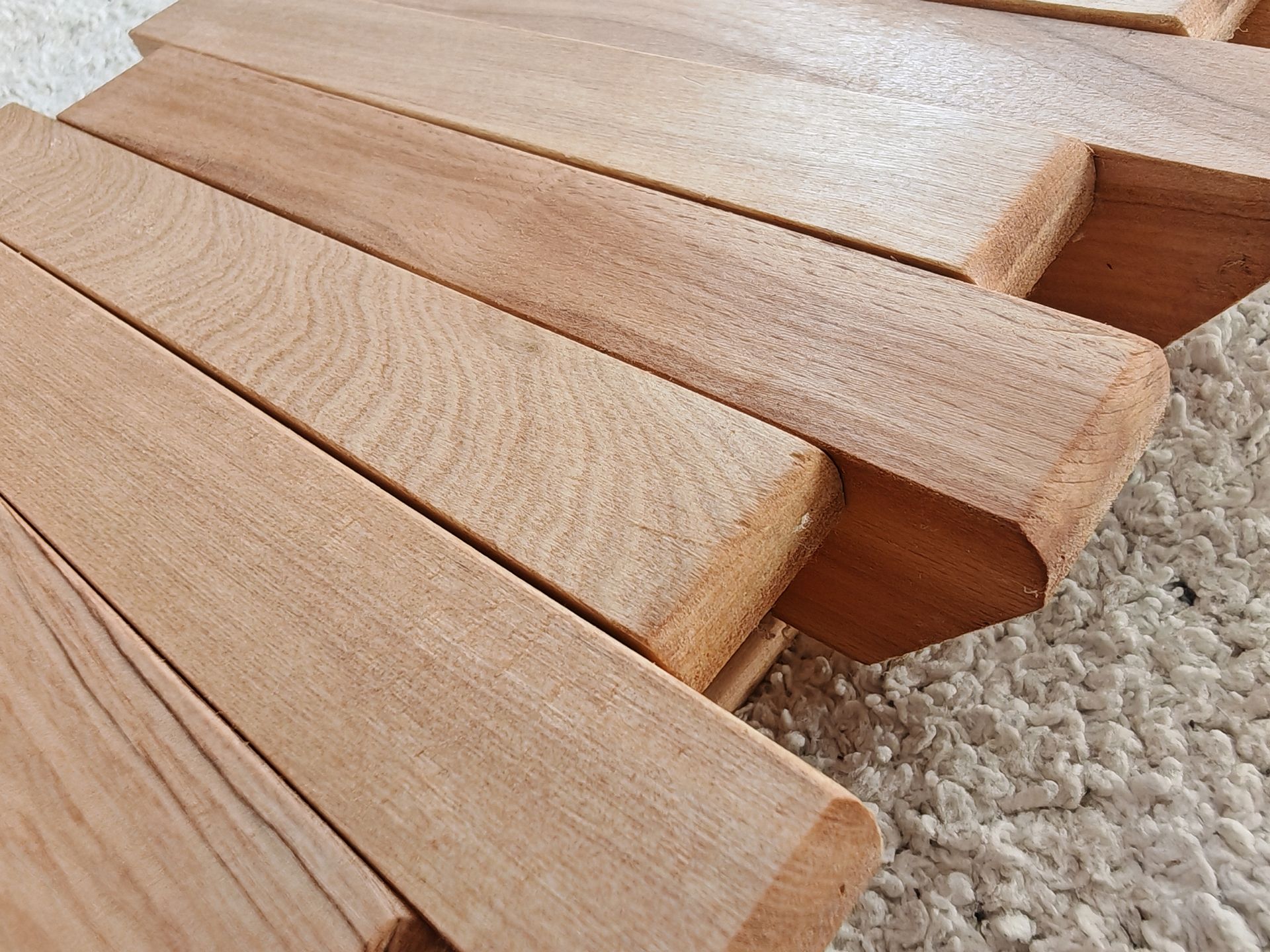 Bloques de madera apilados en una fila inclinada sobre una superficie alfombrada.
