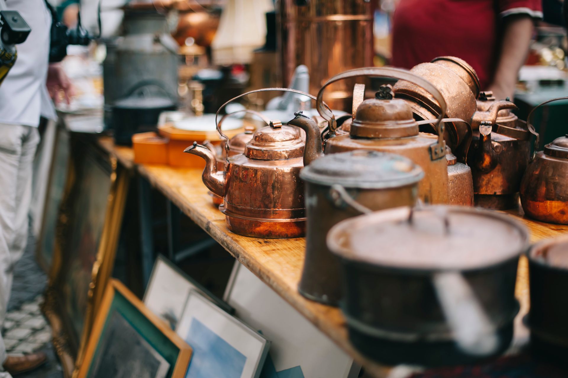 A row of copper pots and kettles on a table at a flea market.