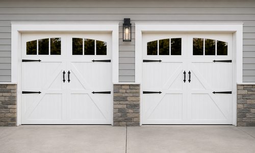 Two white steel carriage house garage doors with Z-brace panels and arched windows on a tan home
