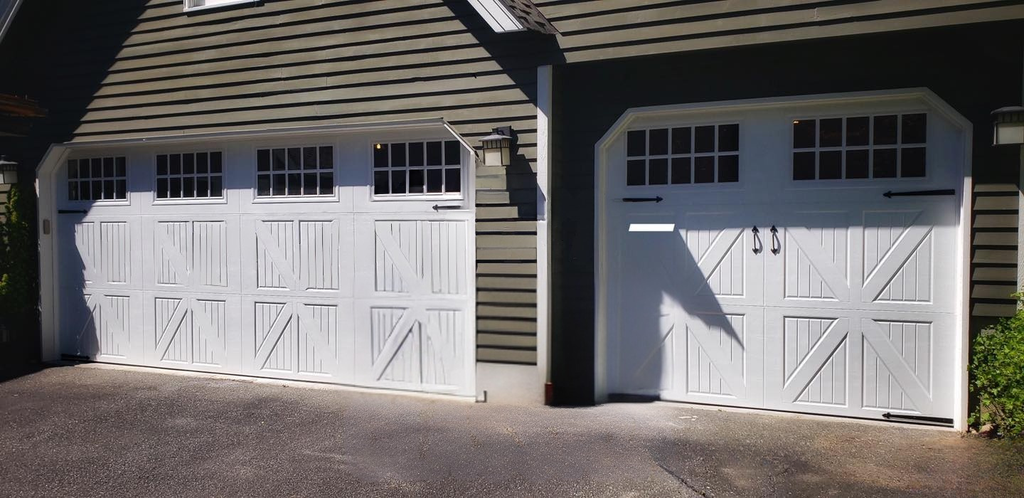Board-and-batten and X-brace steel carriage house garage doors with square windows beside a covered 
breezeway