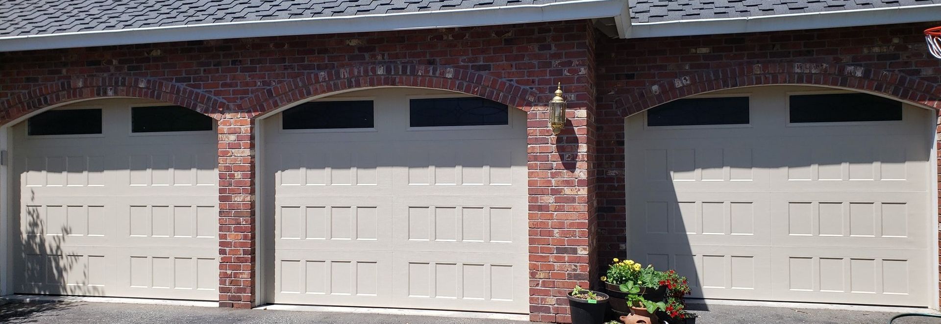 Close-up of tan steel carriage house garage doors on a brick home 
