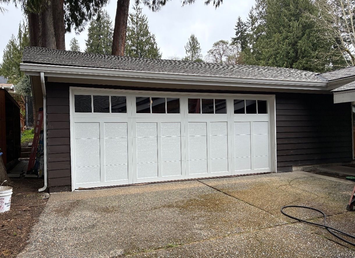 Home with a new white steel carriage house garage door with windows