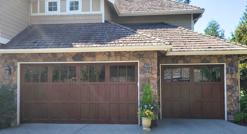 Stone-accented home with two dark wood-tone steel carriage house garage doors flanking a covered breezeway