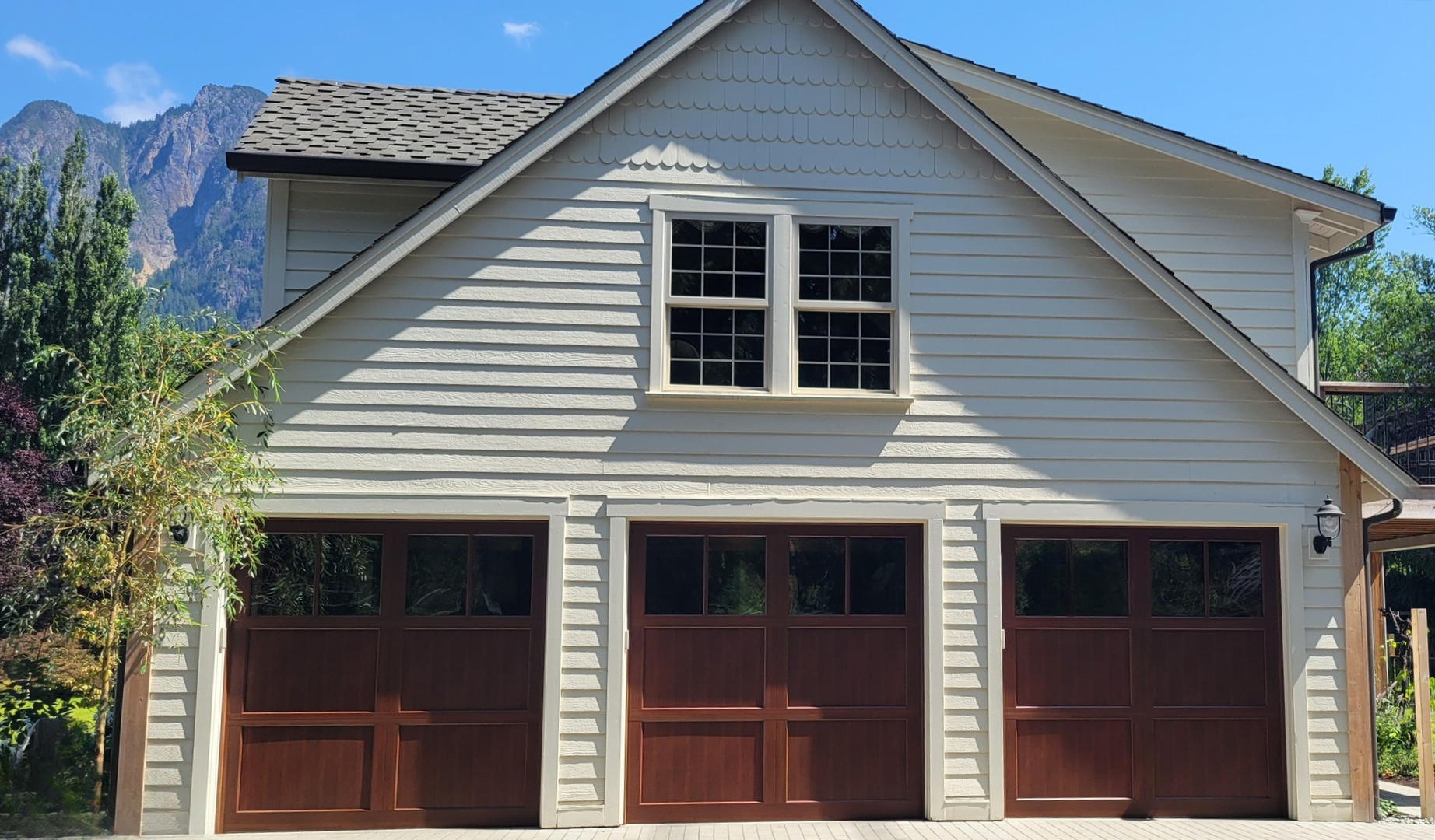 White three-car home with arched wood carriage garage doors