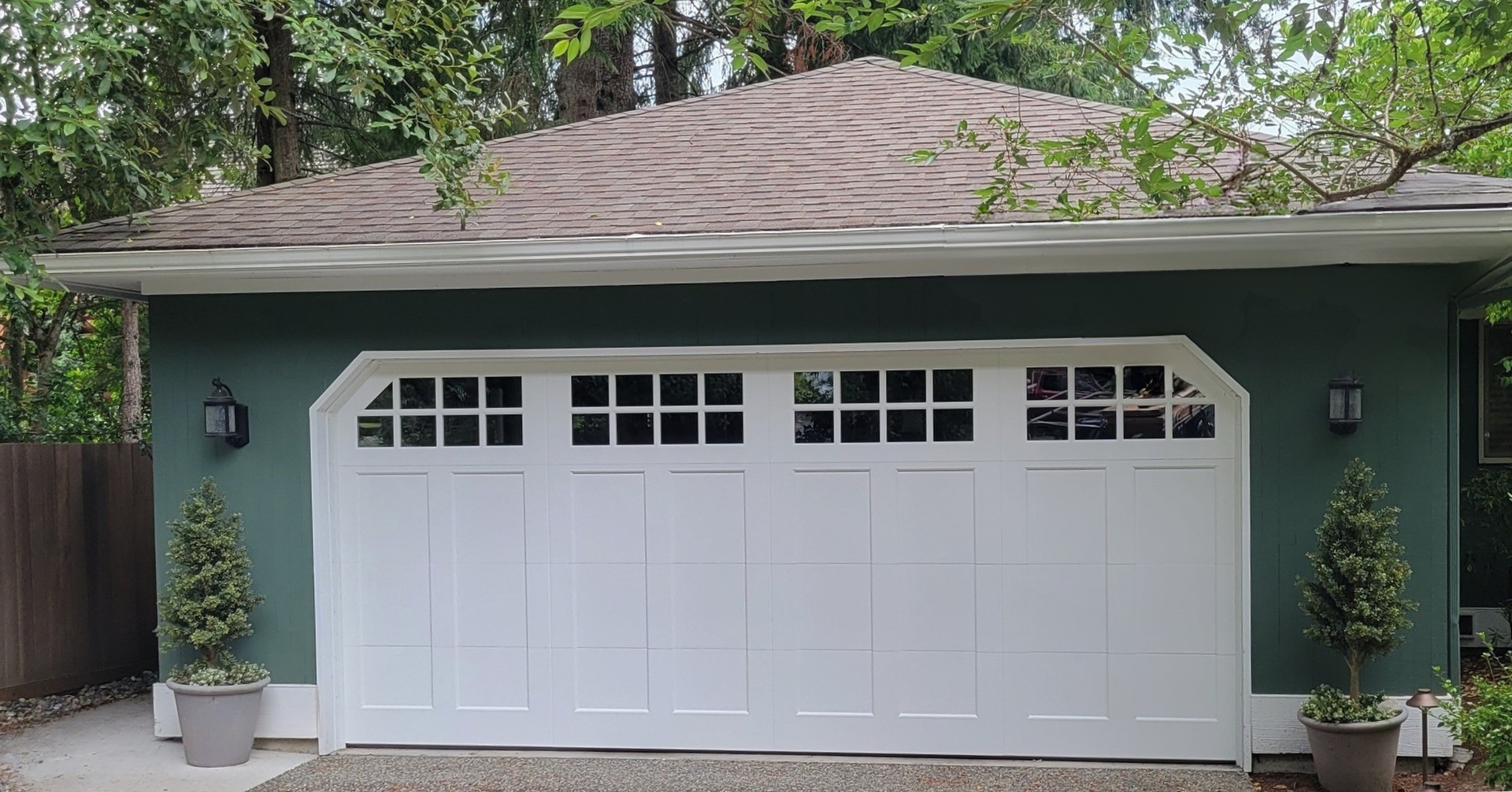 Green home with a new light-colored steel carriage house garage door with windows