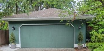 Green home with an old plain garage door before replacement