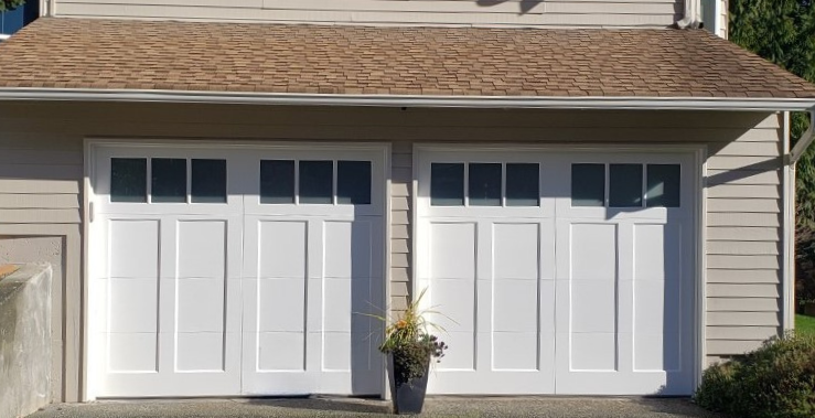 Close-up of a white steel carriage house garage door with decorative hardware and hinges